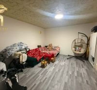 A children's room in a family house with a sofa, a rocking chair, and a floor with a wooden decor.
