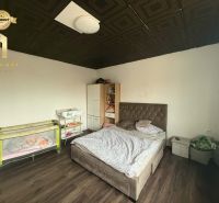 A bedroom in a family house with a wood-decor floor, a bed, and a baby crib.