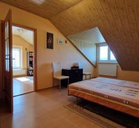 Attic room with a bed, chairs, and a wooden decor floor in a family house.