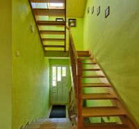 A staircase in a family house with wooden steps, green walls, entrance door.