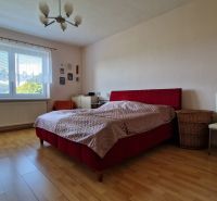 A bedroom in a family house with a double bed and a wooden decor floor.