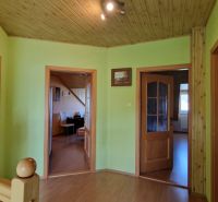 A hallway in a family house with a wooden decor floor, light green walls, and doors.