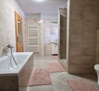 A bathroom in a family house with a bathtub, shower, and ceramic tiles.