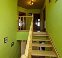 Green staircase in a family house with wooden railing and decorative paintings.