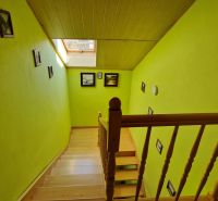 A staircase with wooden railing and green walls in a family house.