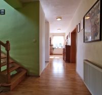Hallway in a family house with a wooden decor floor, staircase, and decorations.