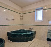 A bathroom with a corner bathtub and double sink in a family house, tiled.