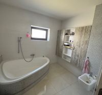 A bathroom in a family house with a bathtub, bidet, and cabinets with a wooden decor.