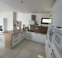 A kitchen in a family house with white cabinets and a wooden decor floor.