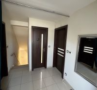 A hallway in a family house with white walls, three dark doors, and a mirror.