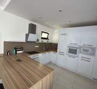 A kitchen in a family house with glossy cabinets and a wooden decor floor.