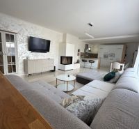 A spacious living room in a family house with a corner sofa and a kitchen counter.