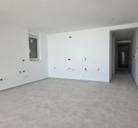 An empty interior of a 3-room apartment with white walls and light flooring.