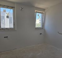 A white interior with two windows in a 3-room apartment, with a wooden decor floor.