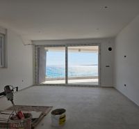 The interior of a 3-room apartment with large windows and a view of the sea.