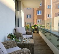 A balcony of a 3-room apartment in Zvolen with garden furniture and glass railing.