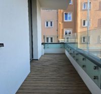 A balcony with glass railings and wooden decor flooring of a 3-room apartment in Zvolen.