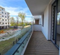 The balcony of a 3-room apartment in Zvolen with a wooden decor floor and a view of the playground.