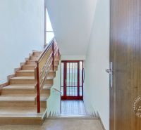 A staircase with a wooden railing in a family house, solid doors, and a skylight.