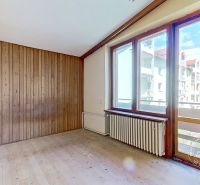 A room in a family house with a wooden decor floor and a view through a large window.