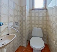 A toilet with a sink and tiles in a family house.