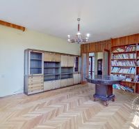 A library and a table in a family house with a wood-decorated floor.