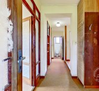 A view of the hallway in a family house with a coat rack and bathroom doors.