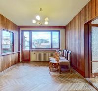 A room in a family house with a large window, a wooden wall, and a floor with a wooden decor.