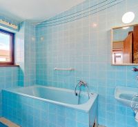 Bathroom with blue tiles, a bathtub, and a sink in a family house.