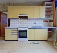 A kitchen in a family house with a gas stove, a sink, and floral patterned wallpaper.