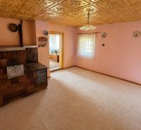 A room in a family house with a tiled stove, light pink walls, decorated ceiling.