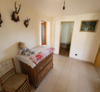 A hallway of a family house with decorations, wooden furniture, and ceramic flooring.