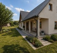 A family house in Vislanka surrounded by a garden and trees, with a sloped roof.