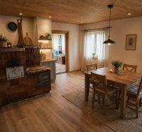 Interior of a family house with a dining table, stove, and wooden decor flooring.