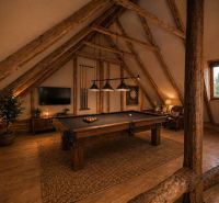 Attic room with a pool table and wood-patterned flooring in a family house.