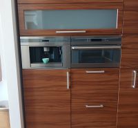 A kitchen unit with a wood decor and built-in appliances in a 2-room apartment.