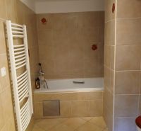 Bathroom in a 2-room apartment with a bathtub and tiled finish, light tones.