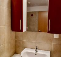 Bathroom in a 2-room apartment with a sink, cabinet, and ceramic tiles.