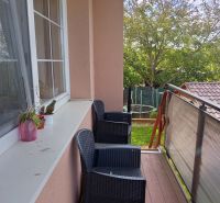 A balcony with plastic chairs and a view of greenery in a 3-room apartment.