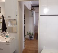 A bathroom in a 3-room apartment with a wooden decor floor and white tiles.