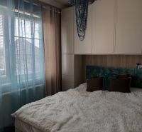 Bedroom in a 3-room apartment with a fluffy bed, curtains, and a decorative chandelier.