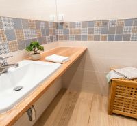 A bathroom with colorful tiles and a wooden decor floor in a 3-room apartment.