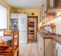 A kitchen in light shades with built-in appliances, a dining table, and a decorated wall.