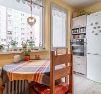 A kitchen in a 3-room apartment with a corner window, a dining table, and a white refrigerator.