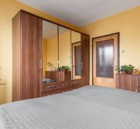 A bedroom in a 3-room apartment with a large wardrobe and wooden decor furniture.