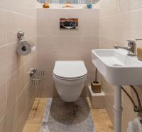 A bathroom in a 3-room apartment with a wooden decor floor and a wall-mounted toilet.