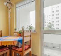 Dining area with a wooden table and chairs near the balcony in a 3-room apartment.