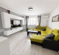 Living room in a three-room apartment with a wooden decor floor and a green sofa.