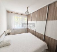 A bedroom in a 3-room apartment with a large wardrobe and a bed, sheer curtains on the window.
