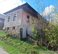 An old stone house in Heľpa, unique property, with a neglected facade and natural surroundings.